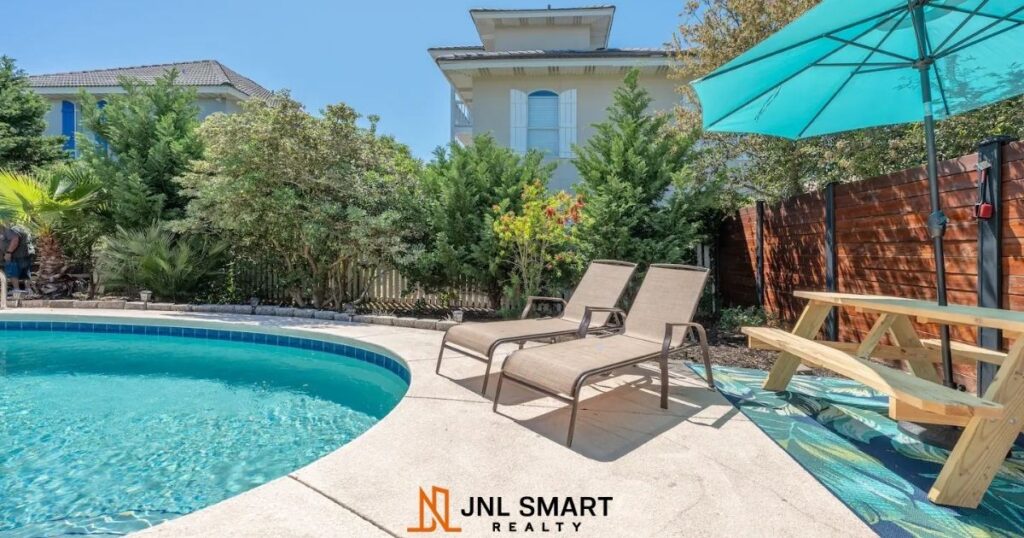 Private swimming pool with umbrella and lawn chairs.
