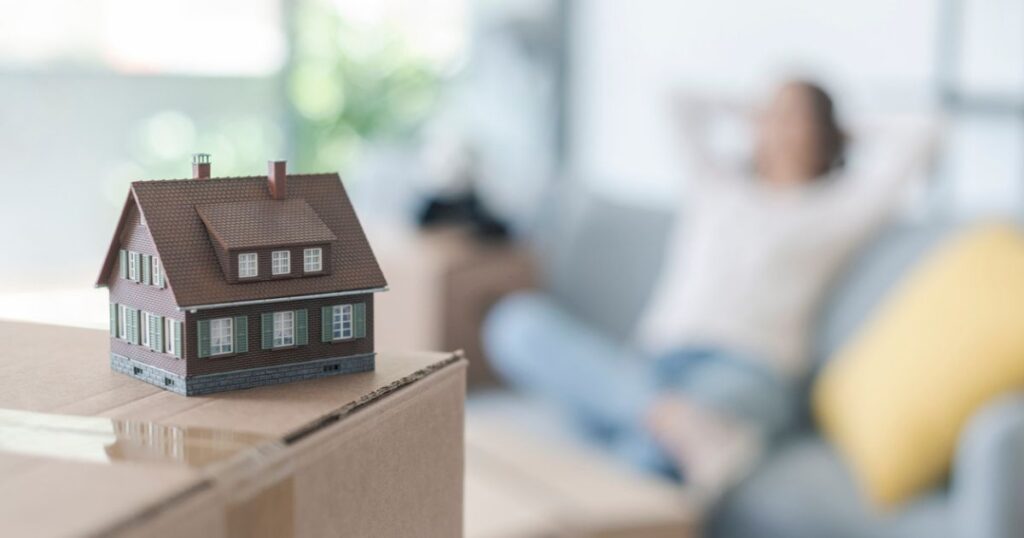 Model of home with person relaxing in the background enjoying revenue from passive income