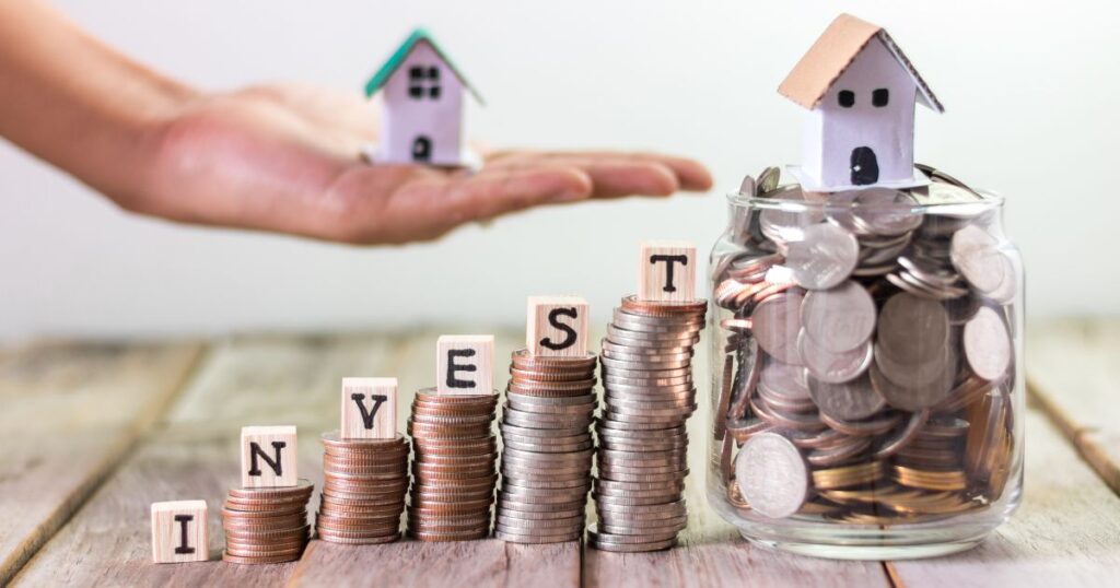 Investing In Real Estate: 7 Reasons To Start Now 3 Jar of coins with scrabble tiles that spell out the word invest leading to a small cardboard house